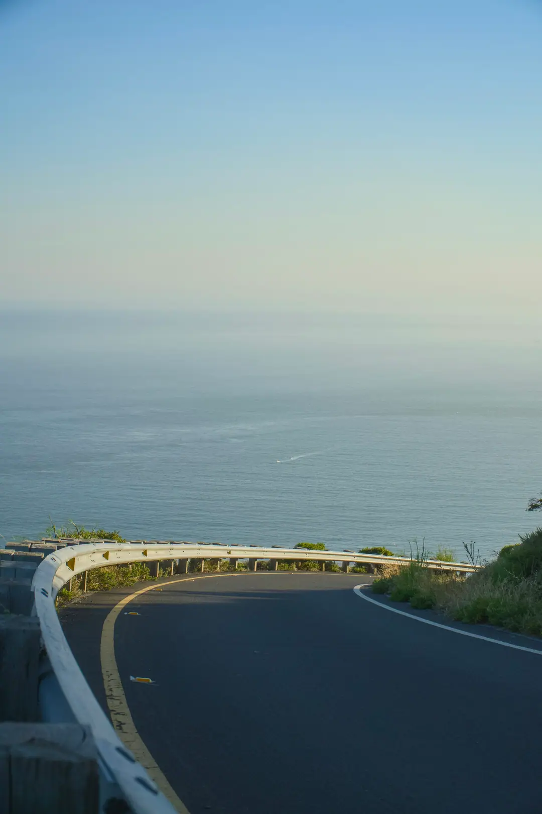 A road curving along a cliff above the ocean on a clear day