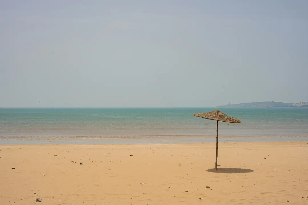 Una sombrilla de paja en la arena vacía de la playa de Essaouira