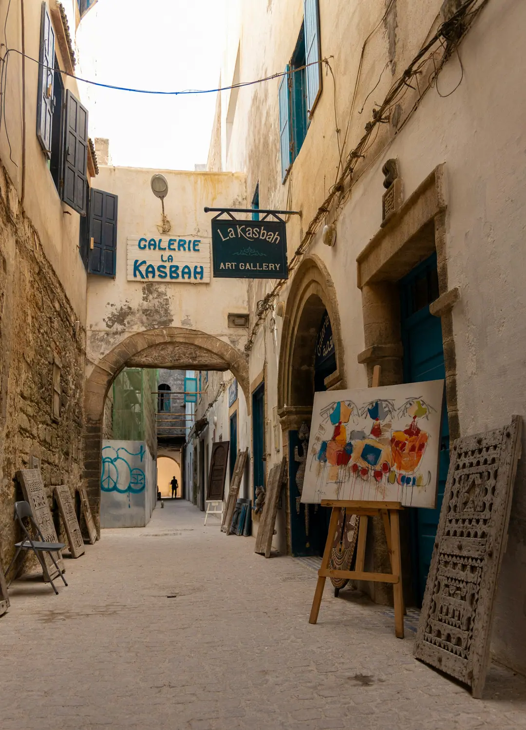 El cartel de una galería de arte y cuadros en un callejón con arcos de la medina de Essaouira