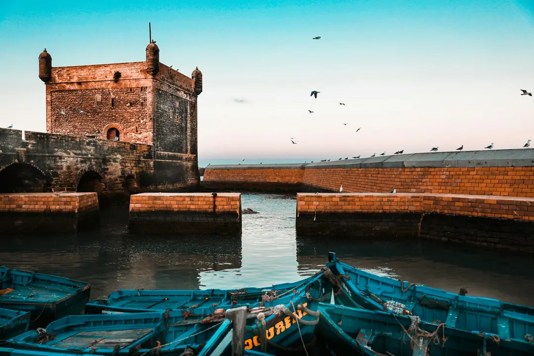The square bastion of Essaouira port above blue fishing boats on a clear day