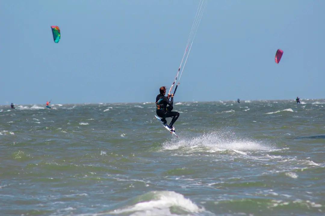 A kitesurfer lifting off the water among other kites on a windy day