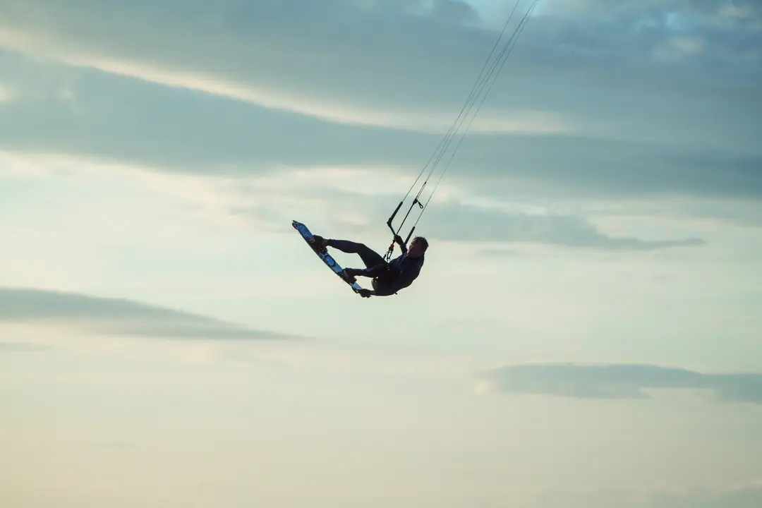 A kitesurfer high in the air mid-jump against the sky