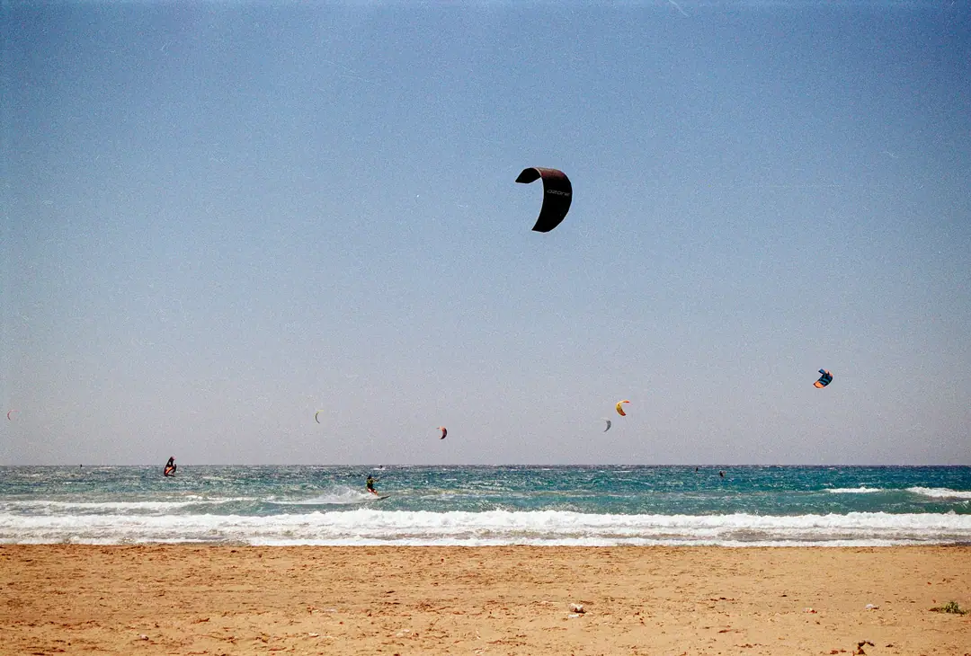 Des kitesurfeurs au large d'une longue plage de sable