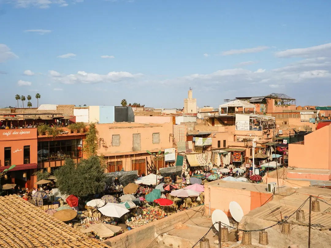 Azoteas y sombrillas del mercado en la medina de Marrakech, con un minarete en el horizonte