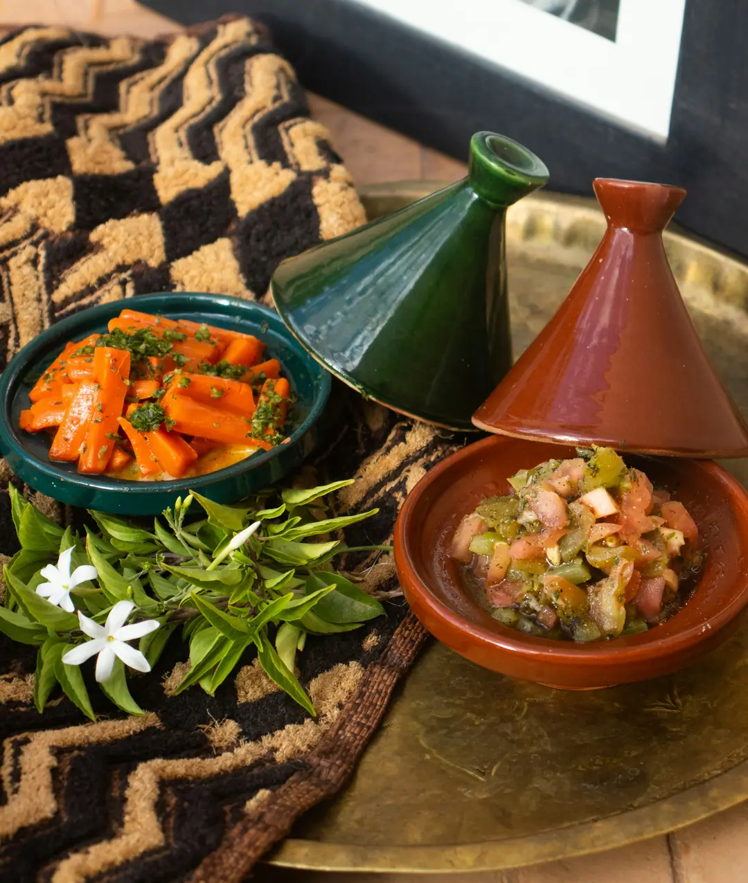 Moroccan tagine pots beside bowls of carrot and tomato salad