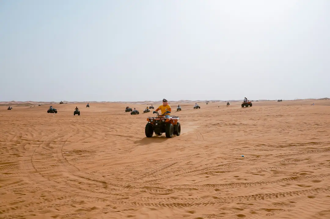 A line of quad bikes crossing a wide sandy plain