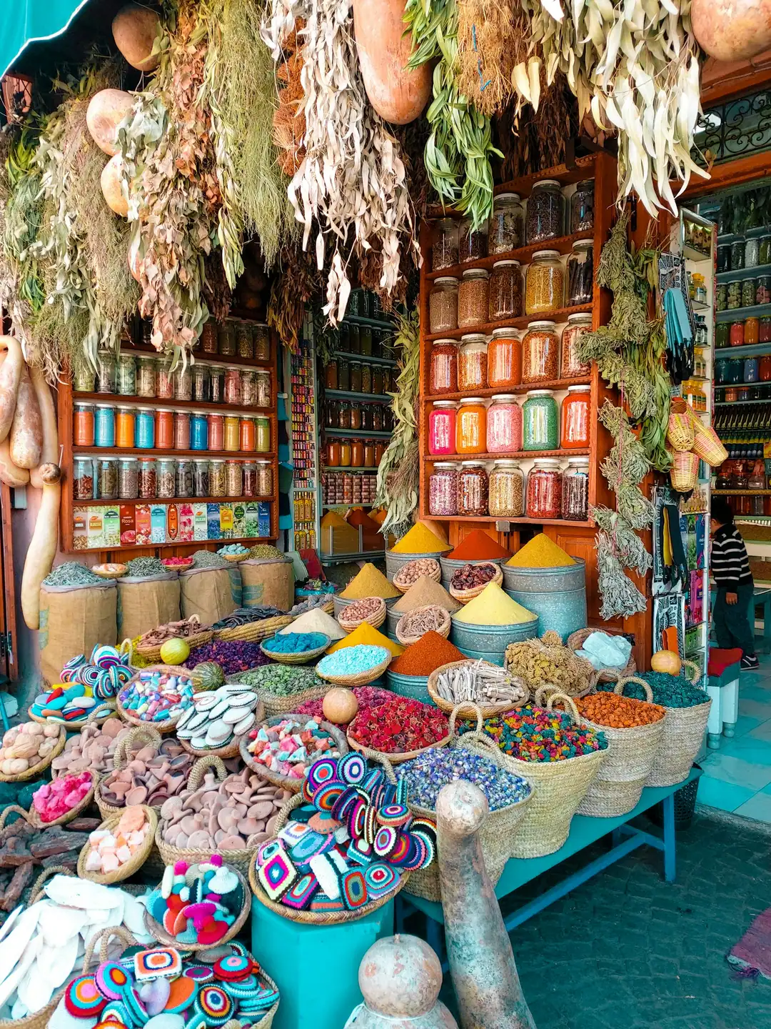 Pyramids of spices, jars and hanging dried flowers at a souk stall