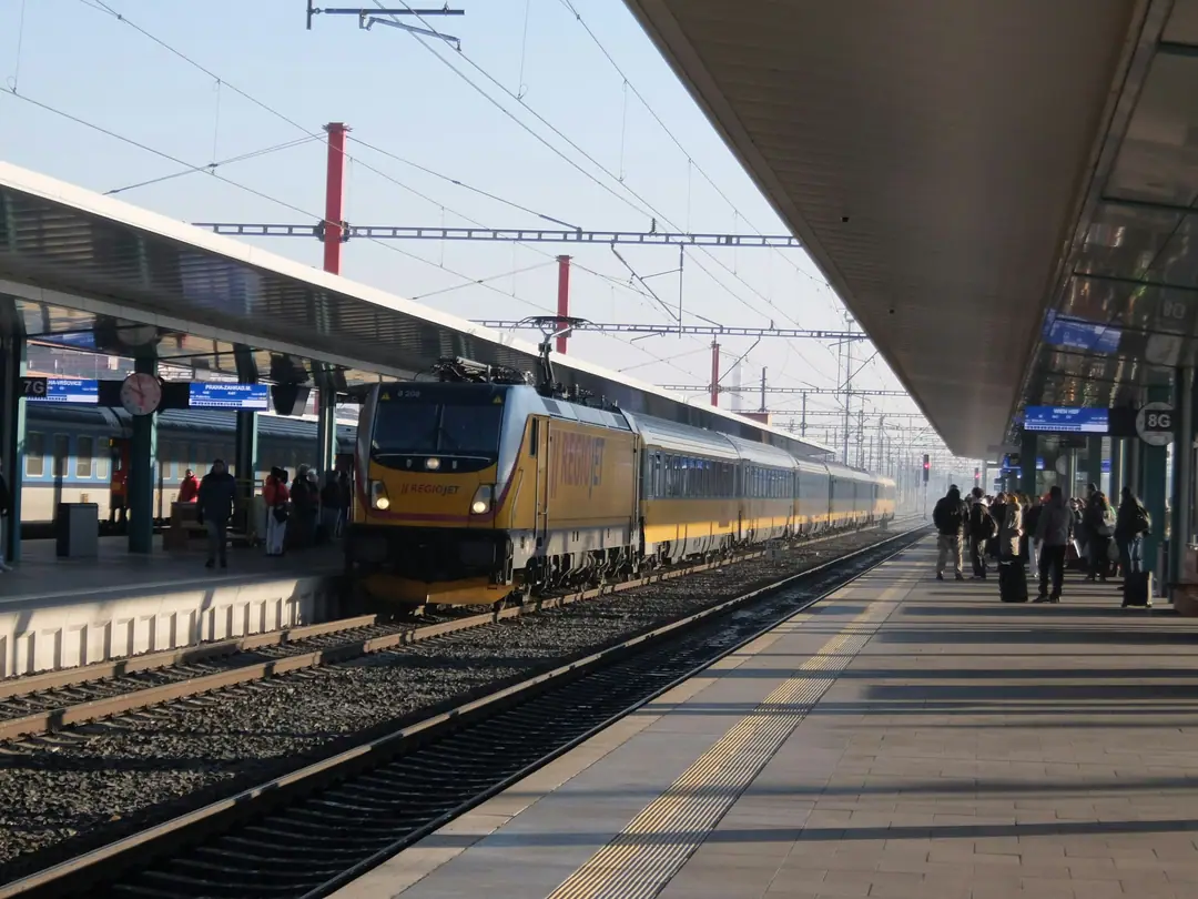 A train at a station platform with passengers waiting